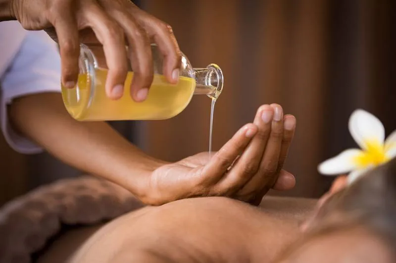 Massage oil poured into a therapist’s hand
